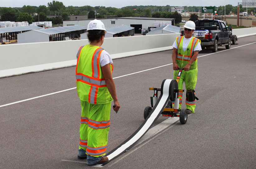 Image of two workers applying permanent tape to a highway